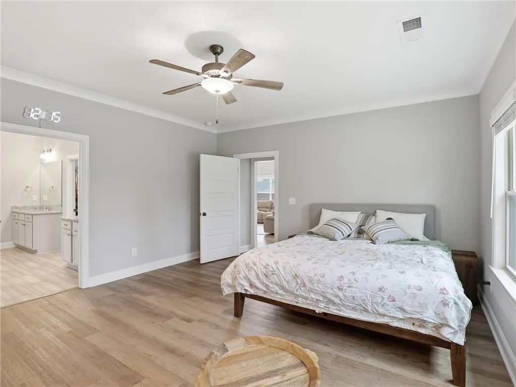 Relax in this tranquil sleeping area, featuring wood-look flooring and a light-filled ambiance.