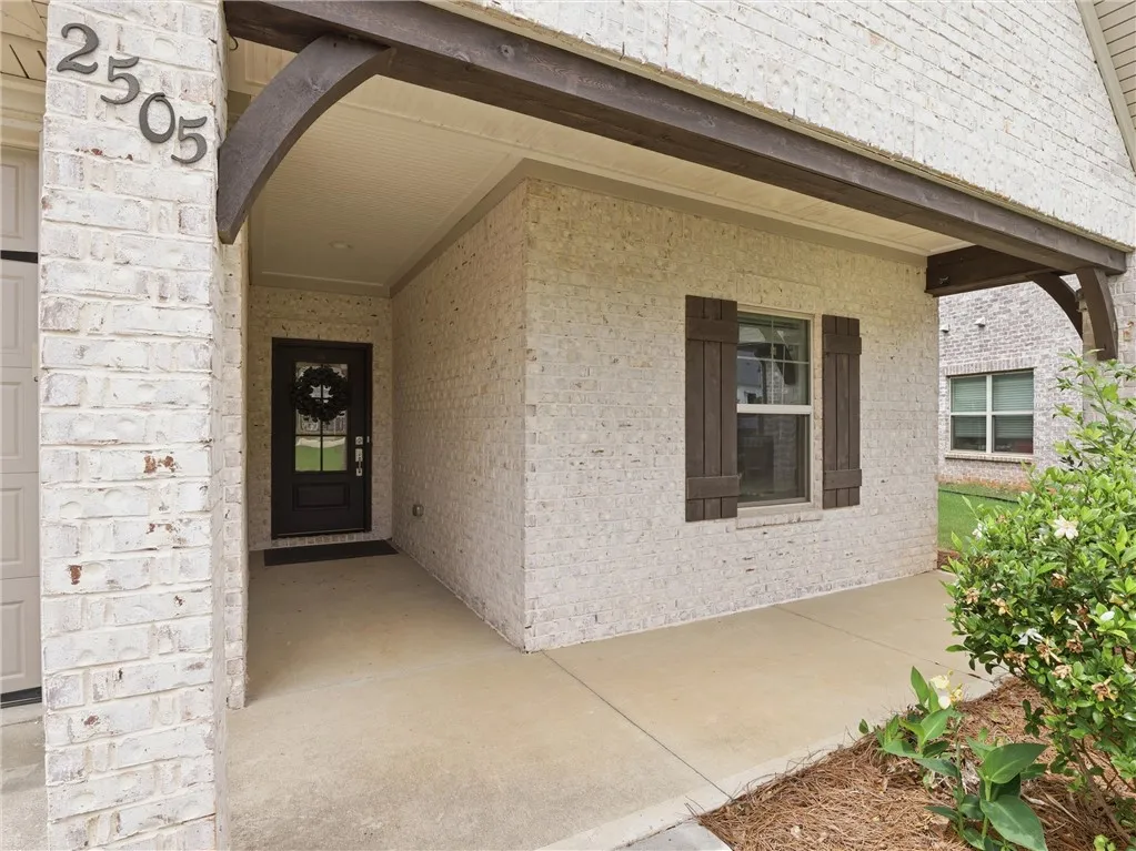 A welcoming front entry features white brick, dark shutters, and a covered porch.