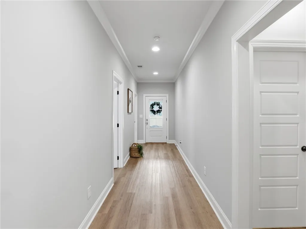 A welcoming entryway hallway offers warm wood-look flooring and recessed lighting.