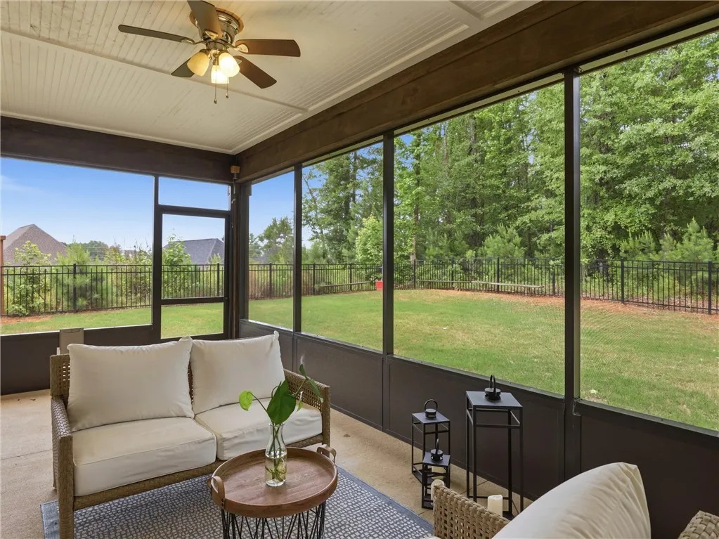 A screened porch overlooking a lush, fenced backyard.