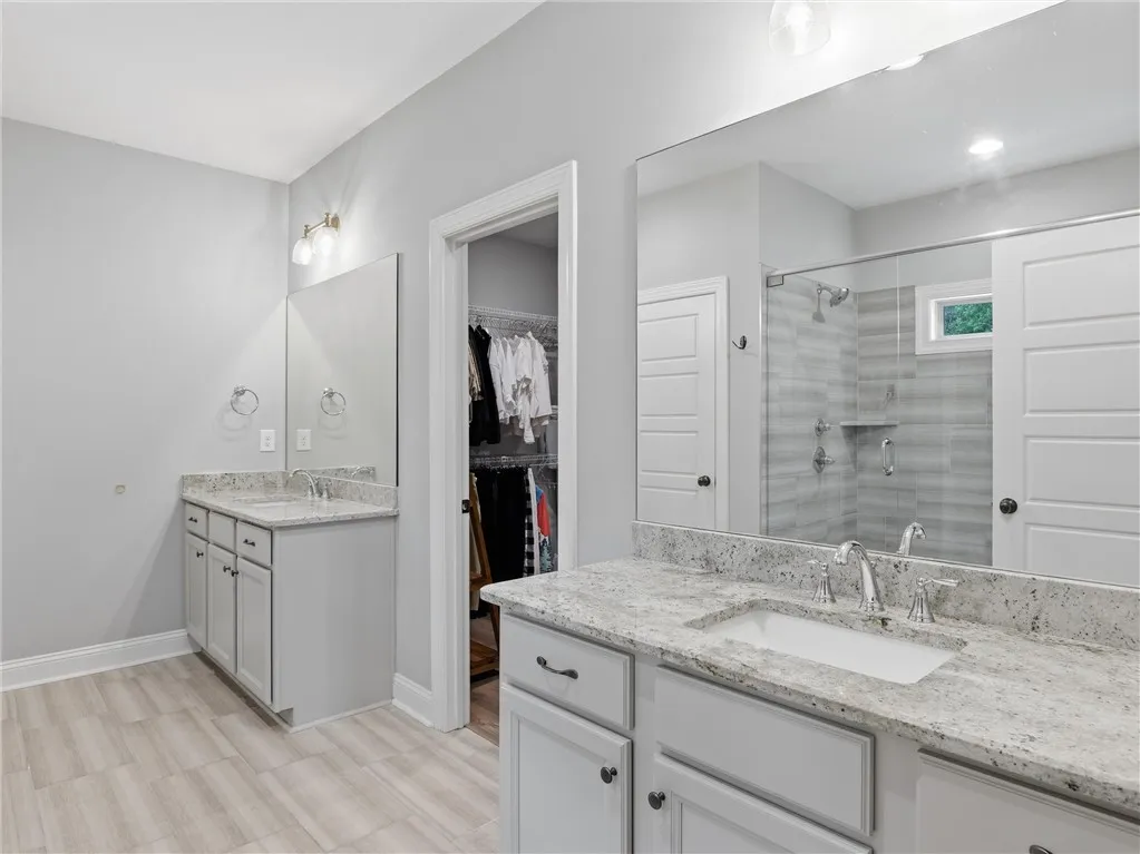 Dual vanities with granite counters provide ample space in this contemporary primary bathroom.
