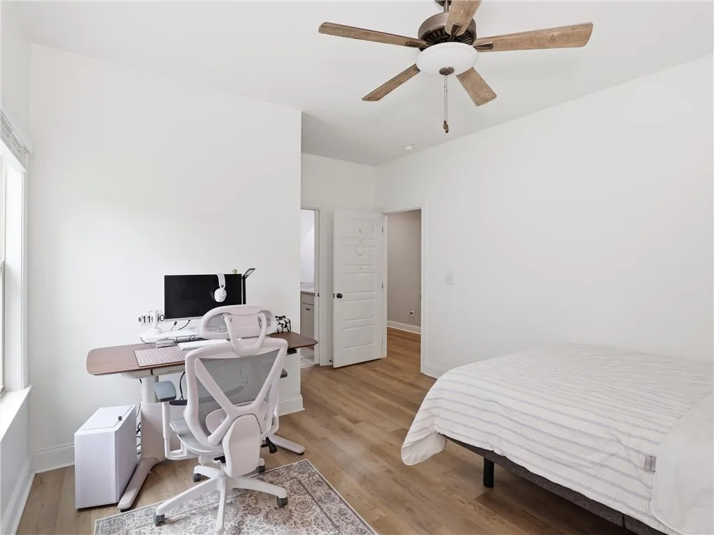 Well-lit room featuring durable hardwood flooring and a functional ceiling fan for optimal comfort.