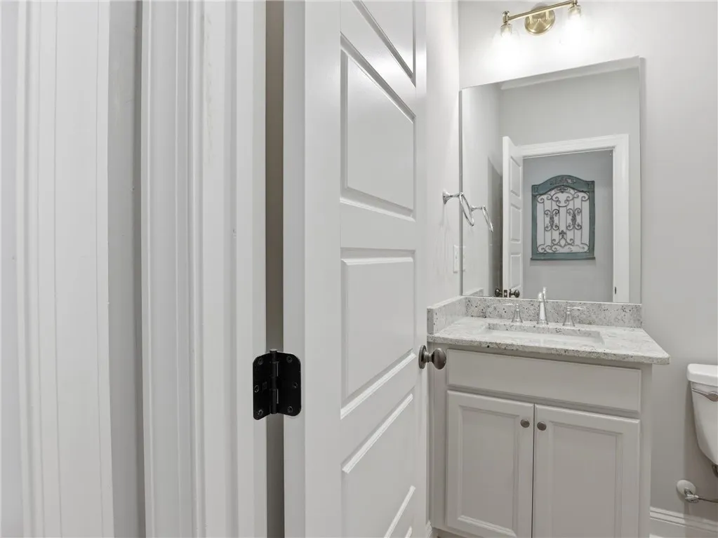 A compact vanity with stone counters and a spacious mirror create an inviting powder room.