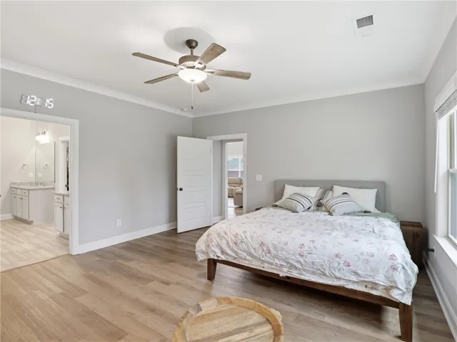 Relax in this tranquil sleeping area, featuring wood-look flooring and a light-filled ambiance.