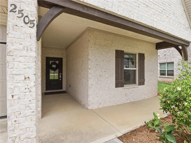 A welcoming front entry features white brick, dark shutters, and a covered porch.