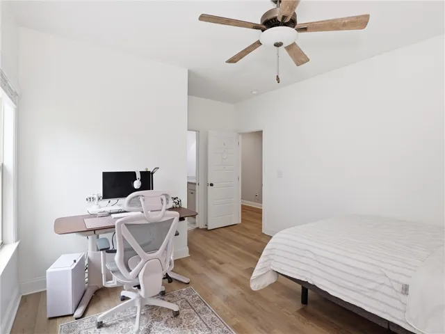 Well-lit room featuring durable hardwood flooring and a functional ceiling fan for optimal comfort.
