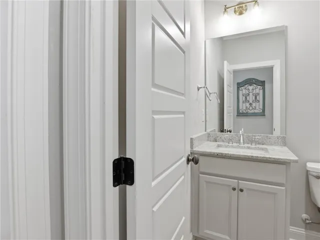 A compact vanity with stone counters and a spacious mirror create an inviting powder room.