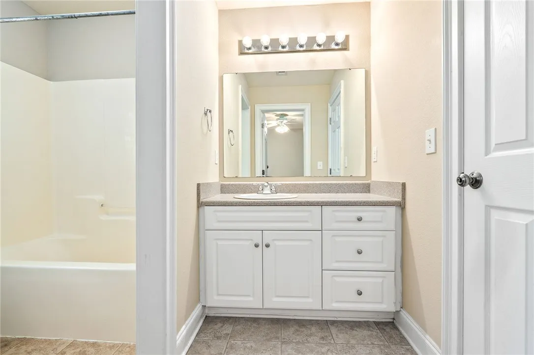 Well-lit vanity with a broad mirror and clean white cabinetry.