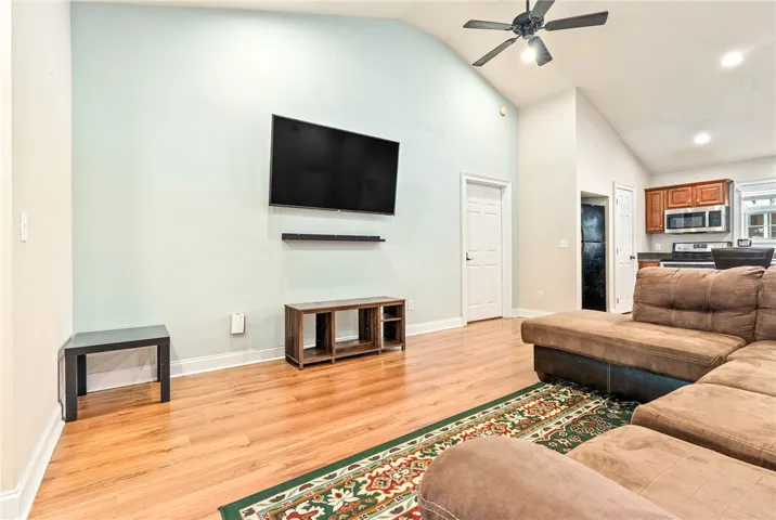 A well-lit gathering space features wood flooring and soaring vaulted ceilings, connecting seamlessly to a functional kitchen.