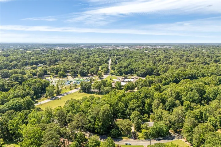 An aerial perspective reveals a vast, tree-lined landscape with a community pool and nearby residential structures.