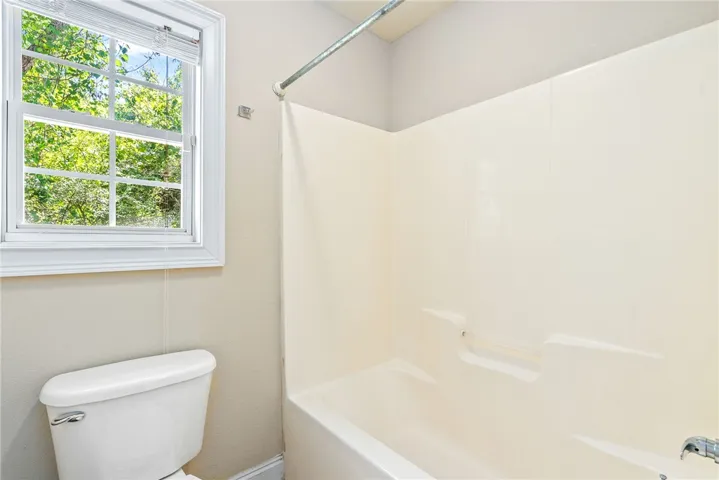A well-lit bathroom provides a window view of lush greenery, ensuring natural light and a refreshing ambiance.