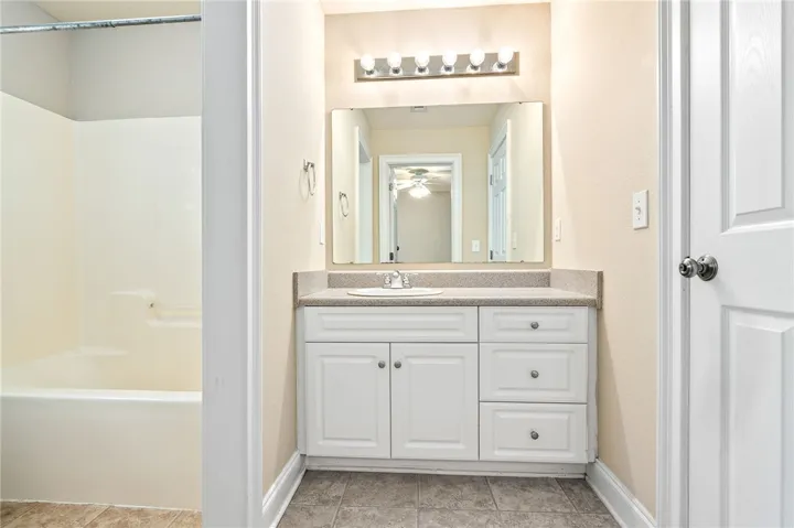 Well-lit vanity with a broad mirror and clean white cabinetry.