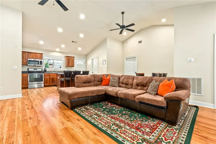An open-concept living space with vaulted ceilings and wood flooring provides a seamless flow for entertaining.