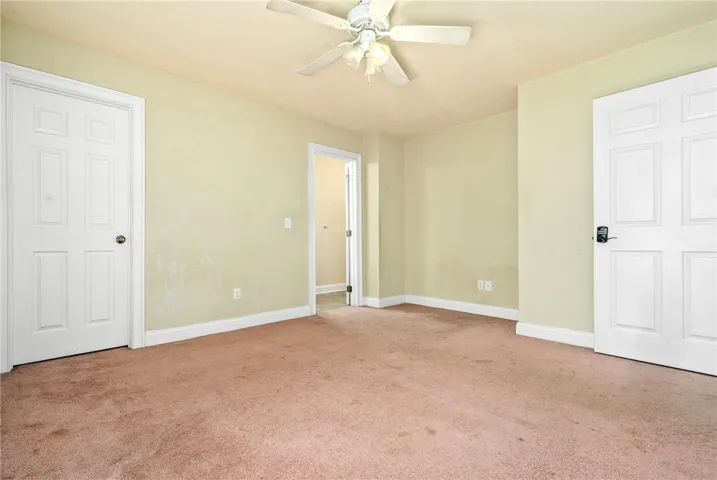 Functional bedroom featuring a ceiling fan and convenient doorways to adjacent spaces.