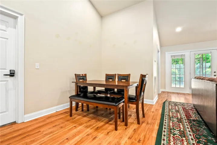 Hardwood floors and soaring ceilings define this dining area, flowing seamlessly to an outdoor vista through glass French doors.
