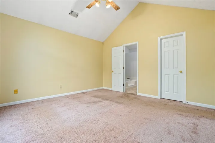 A vaulted ceiling crowns this spacious bedroom, offering direct access to an adjacent bathroom for convenience.