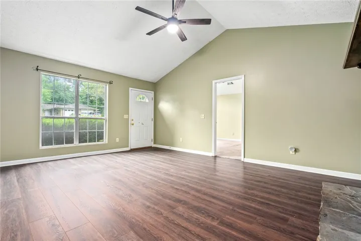 A spacious living room features vaulted ceilings, rich hardwood flooring, and abundant natural light.