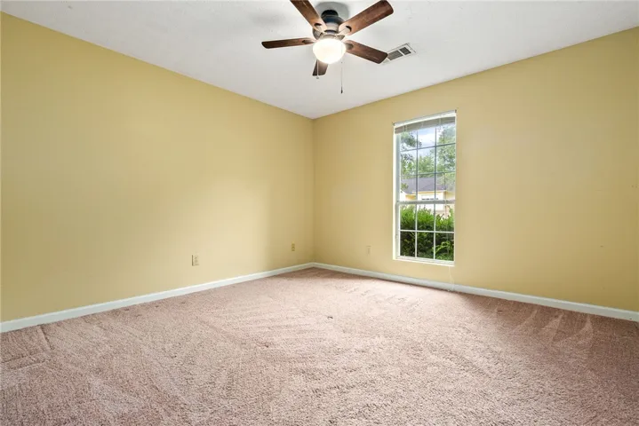 A well-lit bedroom with soft carpeting offers comfortable living space.