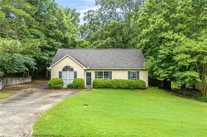 A welcoming facade with a lush green lawn, mature trees, and a practical driveway.