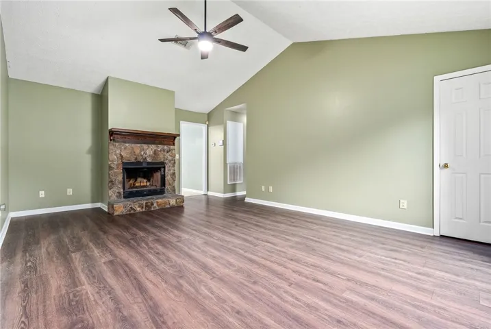 A spacious living room features soaring vaulted ceilings and a stone fireplace, creating an inviting atmosphere.
