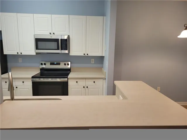 White cabinetry with sleek hardware and modern appliances define this well-appointed kitchen.