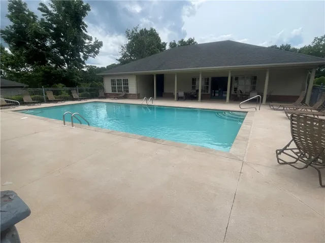 A sparkling pool invites relaxation, set against a clubhouse backdrop with ample space for lounging.