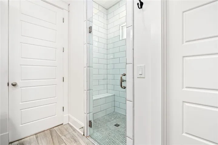 A well-appointed shower stall features clear glass, subway tile, and a built-in bench.