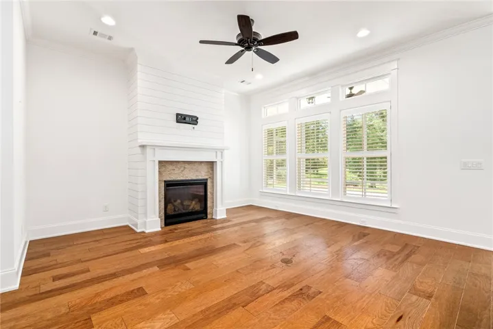 Natural light floods this living space, featuring rich hardwood floors and a cozy fireplace with shiplap accents.
