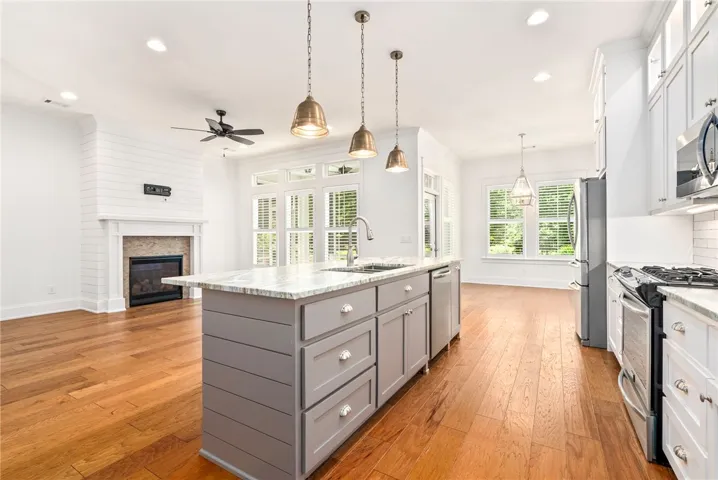 Natural light pours into this modern kitchen and living area, showcasing rich hardwood floors and an inviting fireplace.