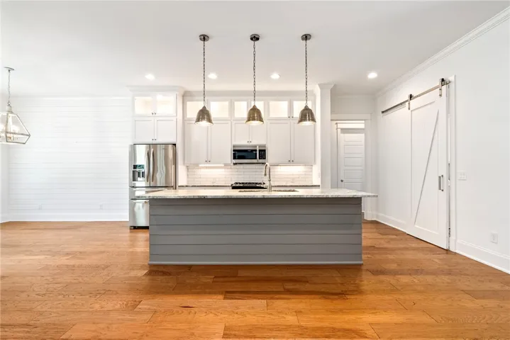 Culinary excellence awaits with a well-equipped kitchen featuring an inviting island and hardwood floors.