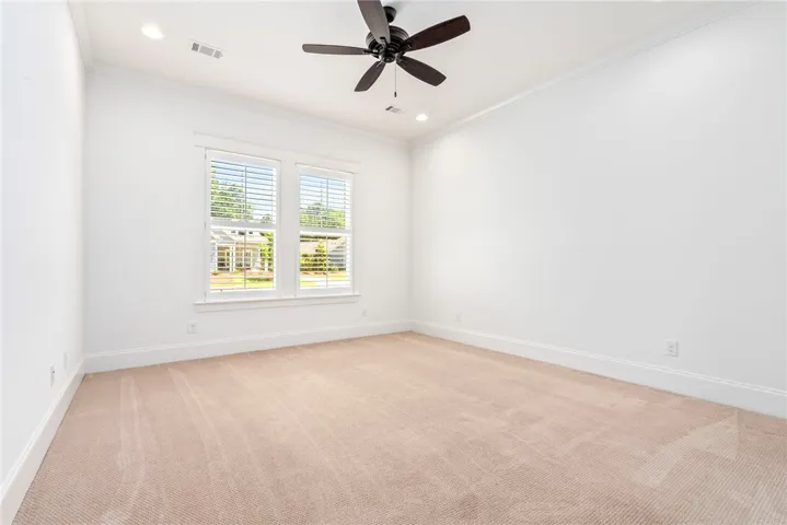 Well-lit interior space with plush carpeting, crown molding, and a ceiling fan.