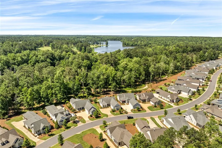 An aerial perspective reveals a serene community nestled beside a shimmering lake and verdant golf course.