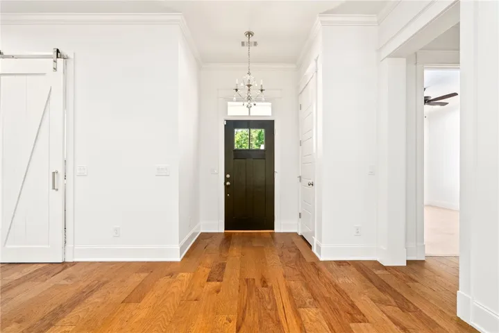 A welcoming entryway with gleaming hardwood flooring and a stylish chandelier.