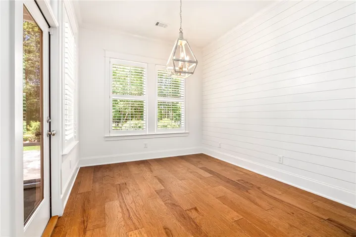 Natural light bathes this versatile room with rich hardwood floors and stylish shiplap accent wall.