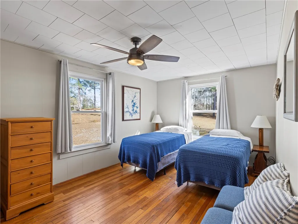 Hardwood floors and bright windows create a cheerful ambiance in this accommodating sleeping space.