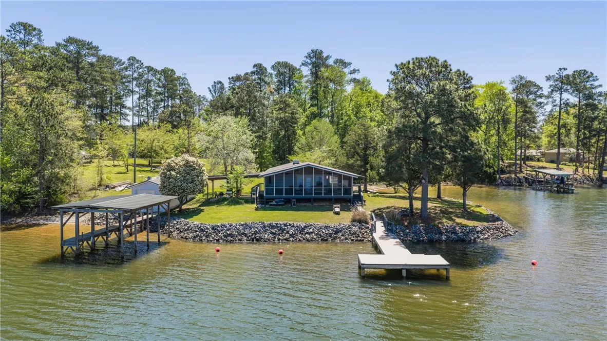 Lakeside home featuring a private dock and sheltered boat slip, nestled among verdant trees.