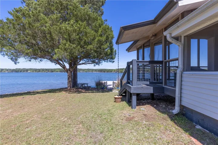 Lakeside home featuring a private dock and mature trees for shaded outdoor enjoyment.