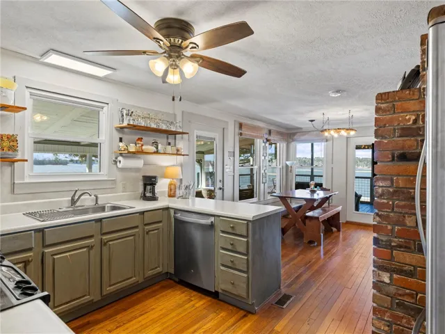 A well-lit kitchen with open shelving flows into a dining area featuring scenic water views.