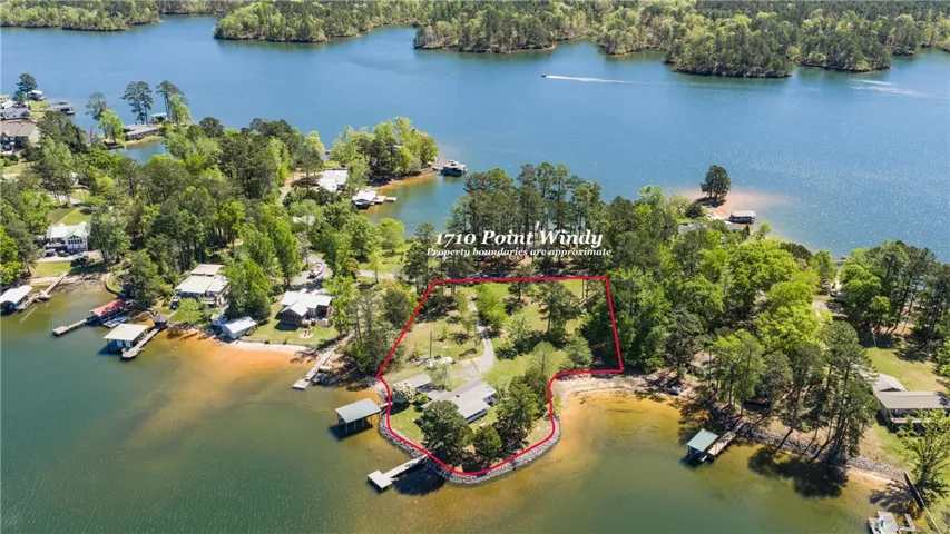 A lakeside property with extensive waterfront, featuring a private dock and mature trees.