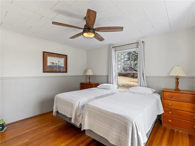 Hardwood floors and a bright window elevate this comfortable, well-lit bedroom.