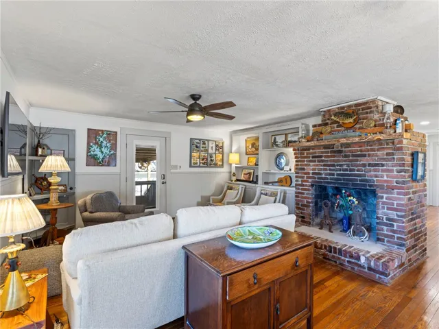 A welcoming living area boasts a robust brick fireplace and polished hardwood flooring.