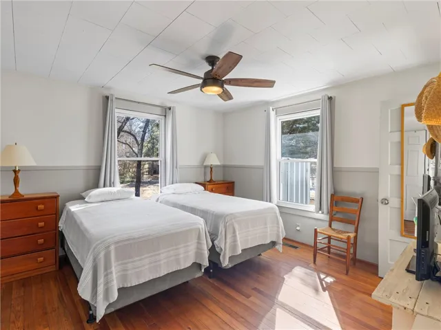 Hardwood floors and a ceiling fan complete this cozy bedroom.