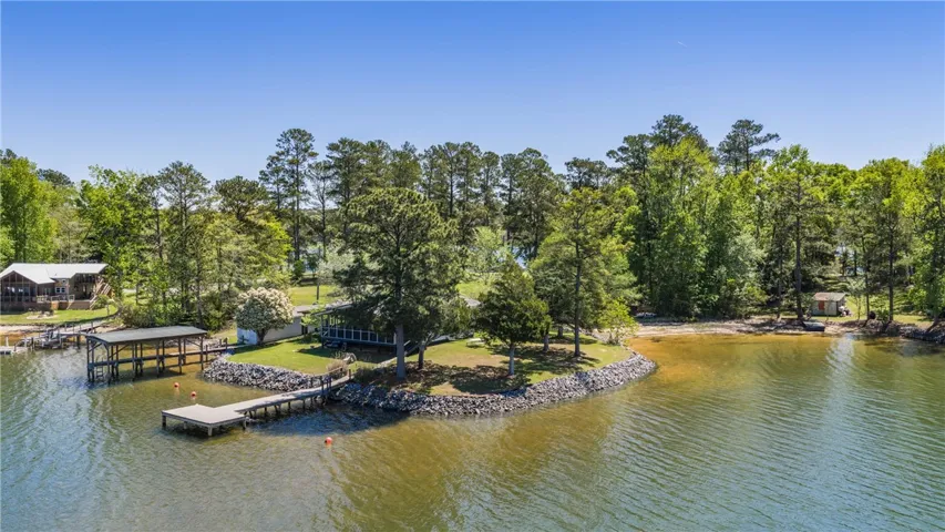 A tranquil lakefront property featuring a private dock and mature trees.