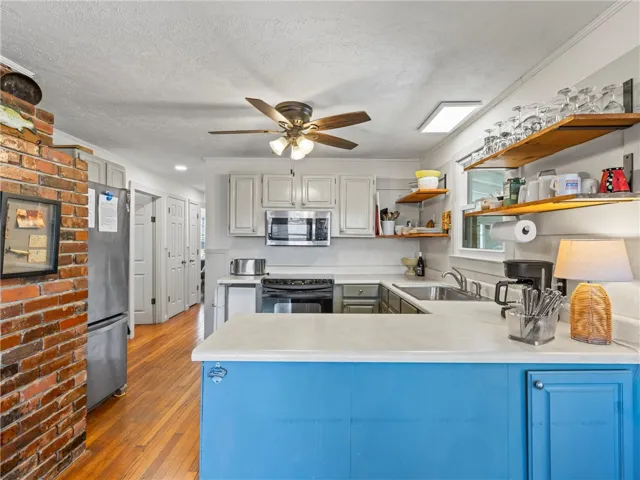 A cheerful kitchen featuring a vibrant blue island and rich hardwood floors.