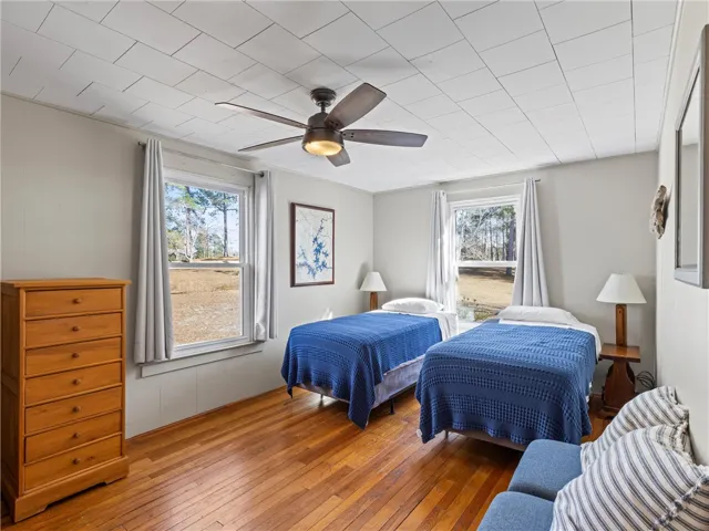 Hardwood floors and bright windows create a cheerful ambiance in this accommodating sleeping space.