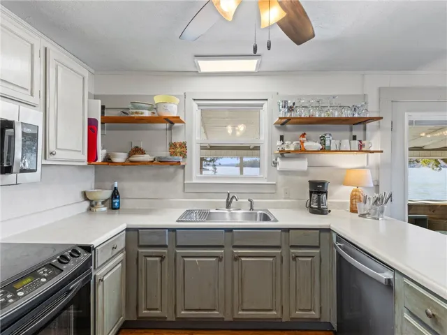 A well-equipped kitchen features a stainless steel sink and a window overlooking a tranquil lake.