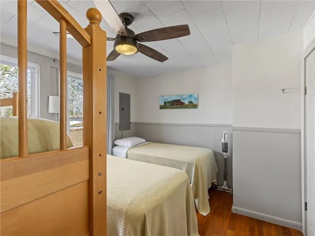 Hardwood floors and bright windows illuminate this comfortable, well-lit bedroom.
