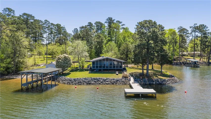 Lakeside home featuring a private dock and sheltered boat slip, nestled among verdant trees.