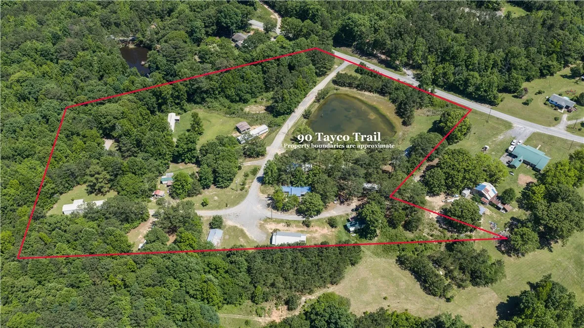 An aerial perspective showcases a large, verdant lot featuring a private pond and ample space for development.