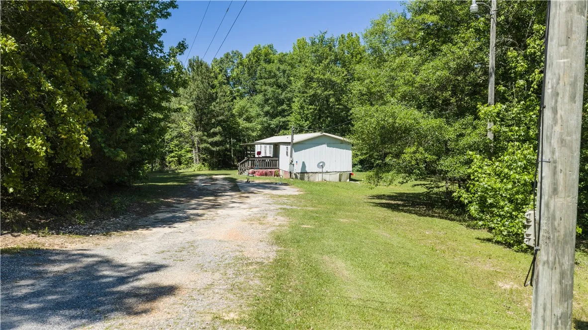 A private driveway leads to a modest dwelling, nestled among a lush, verdant treeline.